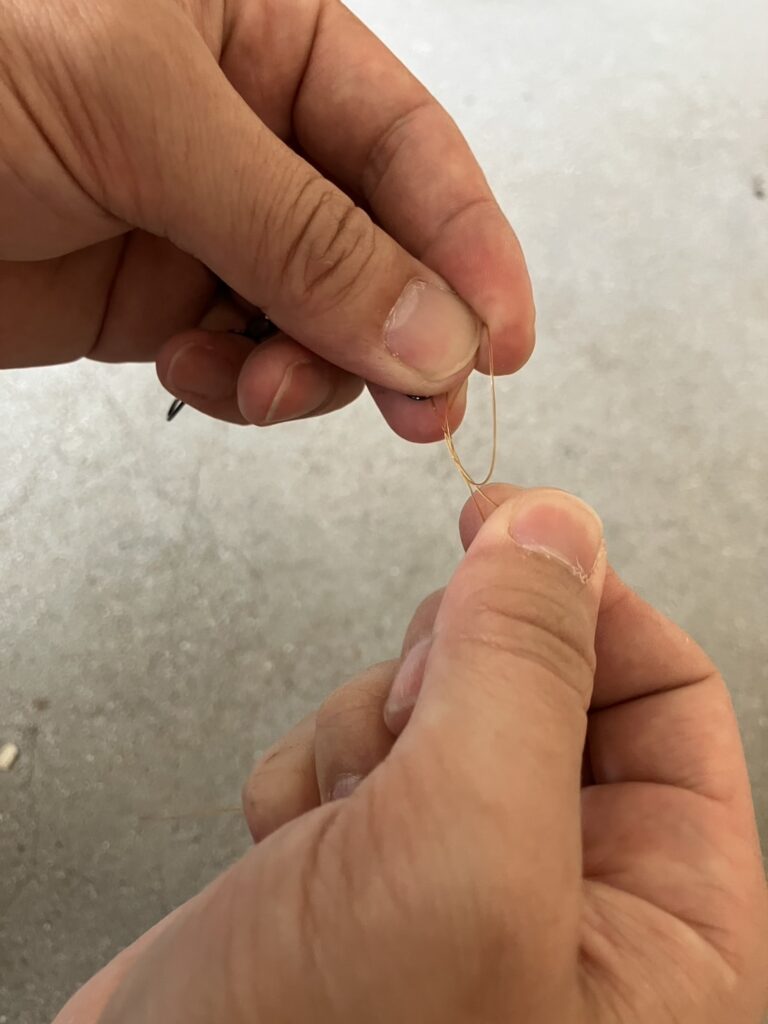 作った輪と元糸を巻き込むように、先端側の糸を3〜4回輪の中を通します。